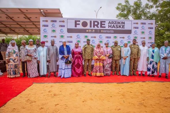 Photo de groupe des officiels devant le panneau de la Foire Arzikin Haske